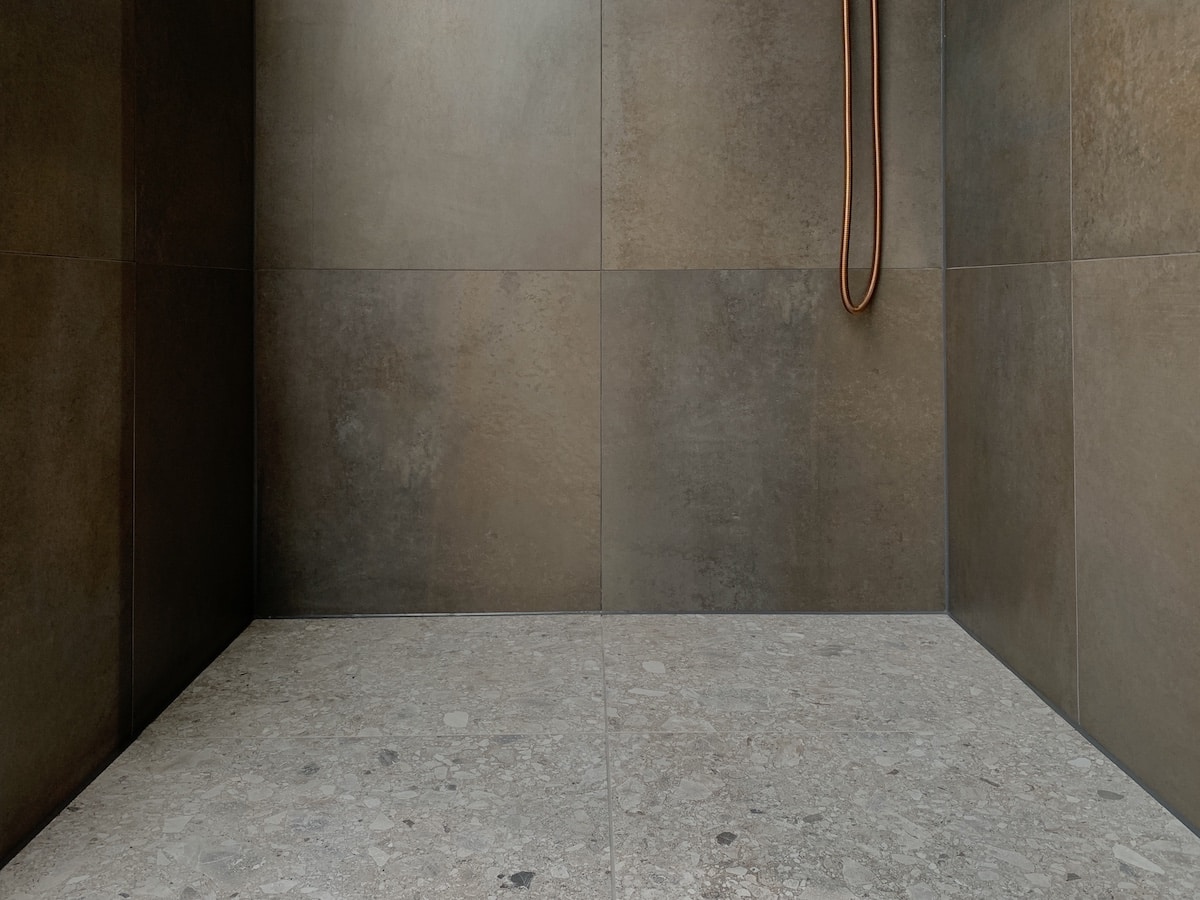 Terrazzotegels op een douchevloer met metallook wandtegels