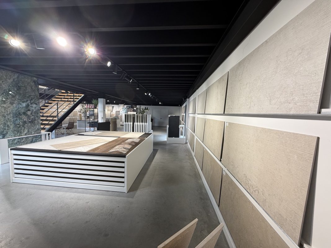 De showroom met tegelwanden, presentatietafel en de entresol