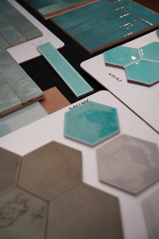 Turquoise tegels met handvorm-look en zeshoeken op stalenborden in de showroom van Tegels & Laminaat