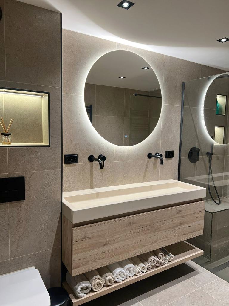 Badkamer met Limestone Beige tegels, houten badmeubel en ronde verlichte spiegel