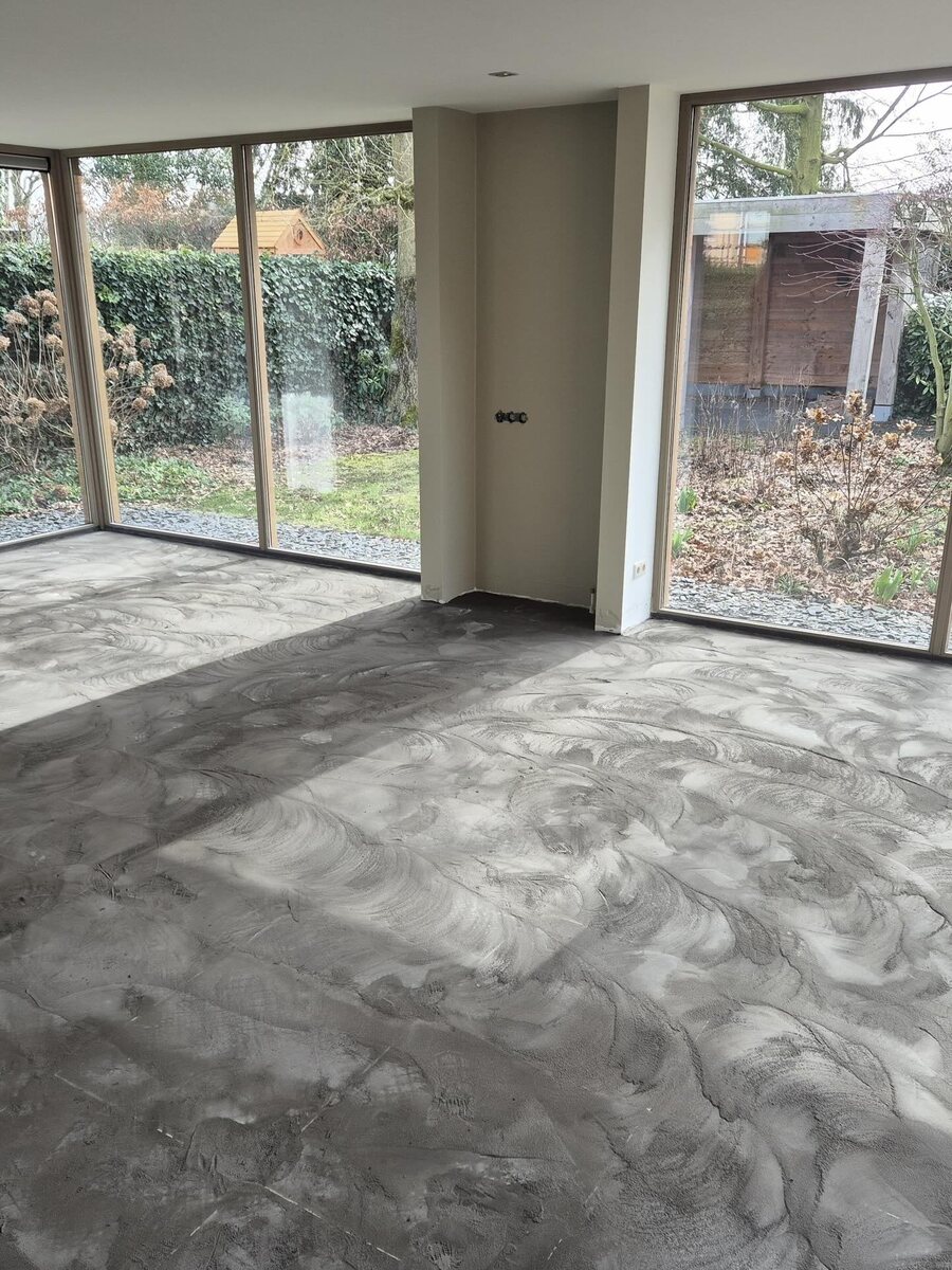 Woonkamer met een ruwe, ongelijke dekvloer voordat er wordt geëgaliseerd