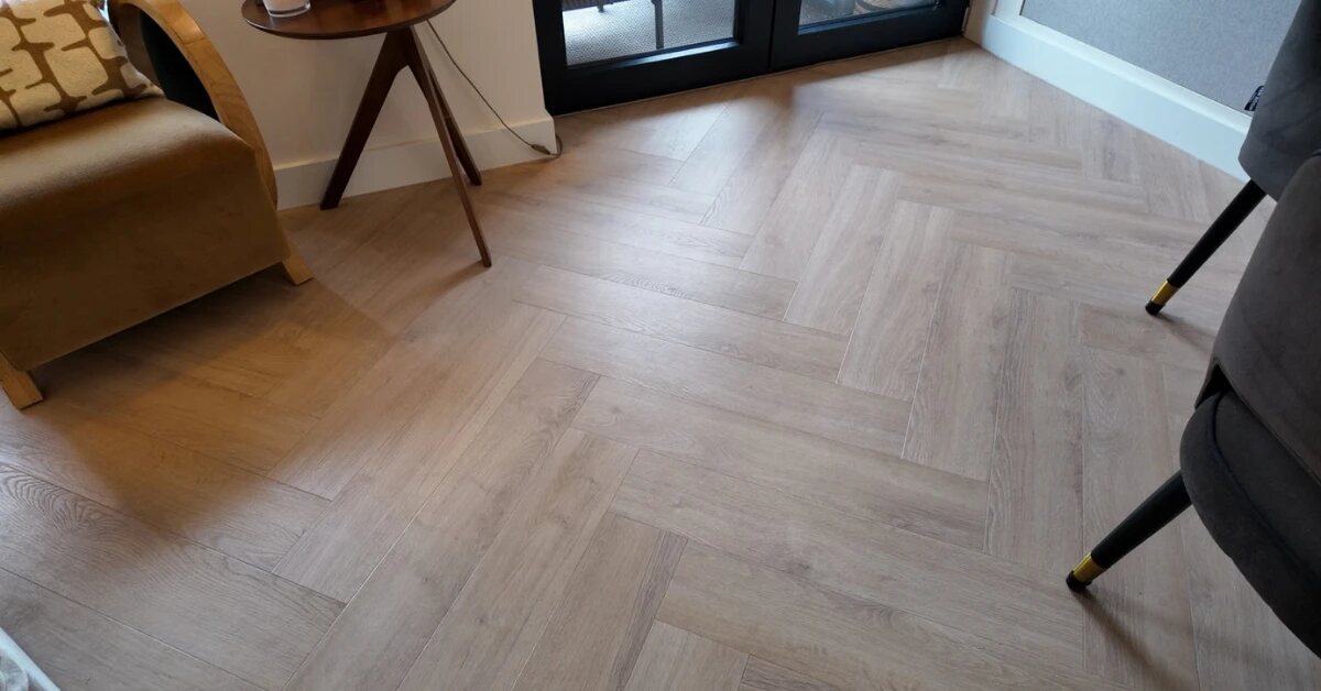 Zithoek met een fauteuil en een lichte visgraatvloer bij de tuindeuren