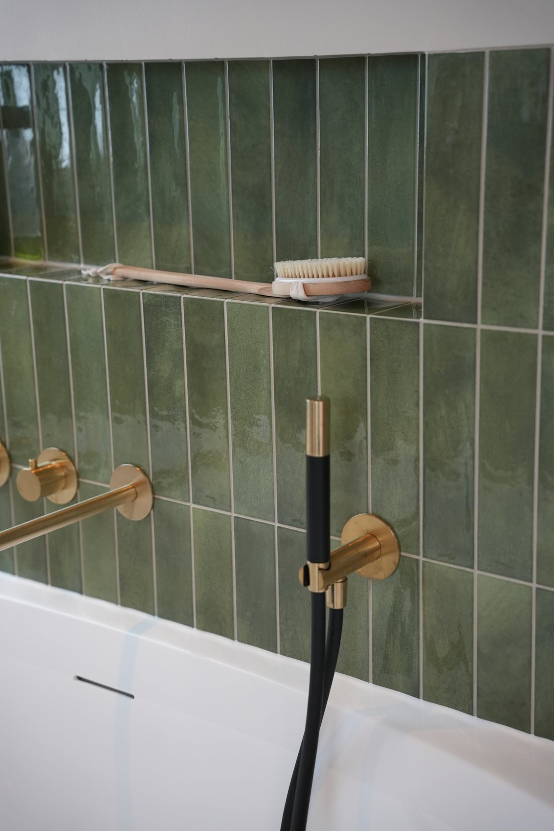 Bad met groene staande wandtegels en kranen van Hotbath in de showroom