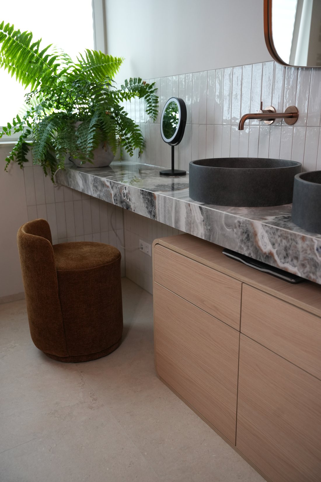 Badmeubel met natuursteen blad, betonnen waskommen en koperen kranen in de showroom