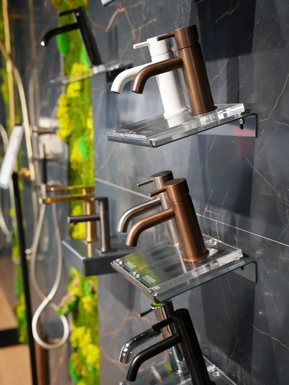 Kranen van Hotbath in koper, wit en zwart op een marmerlook wand