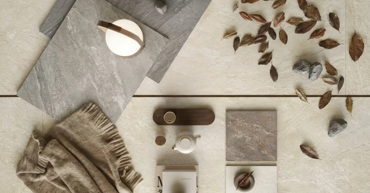 Natuursteenlook tegels in grijs en beige met herfstbladeren, een lamp en een plaid