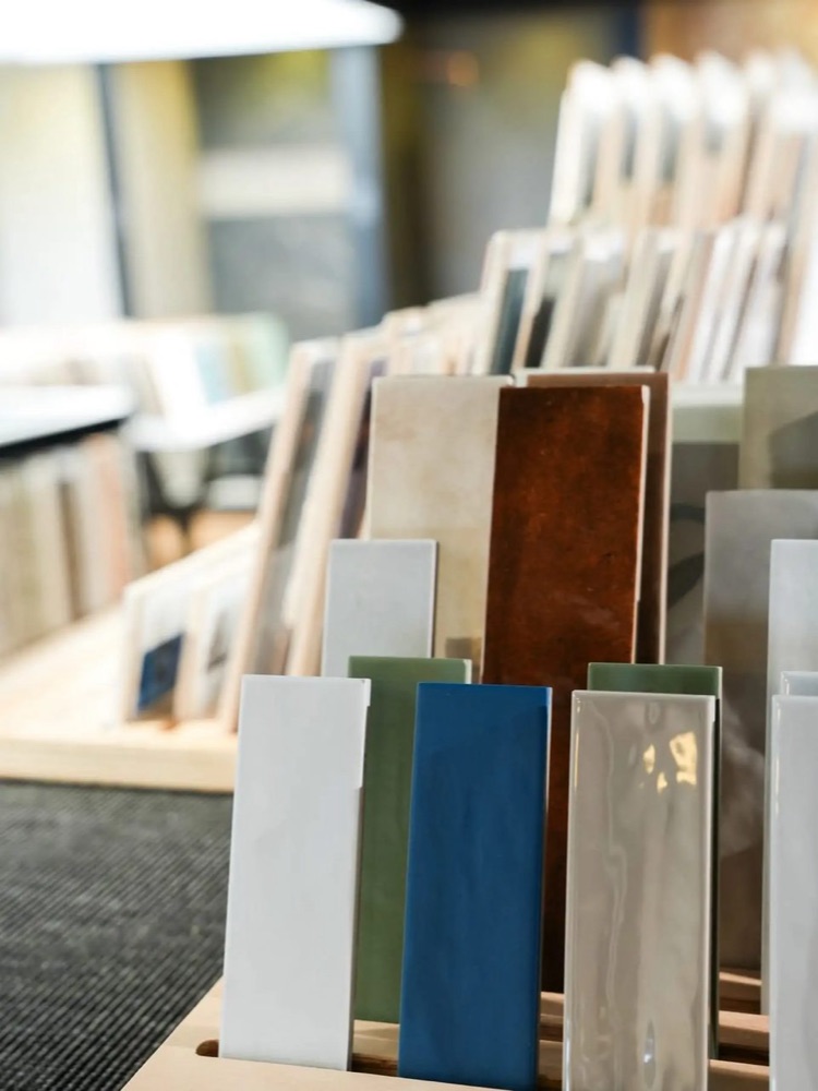 Wandtegels in allerlei kleuren naast elkaar in een rek in de showroom